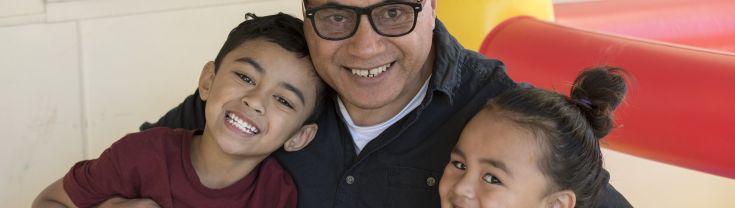 A man with his arms around two children